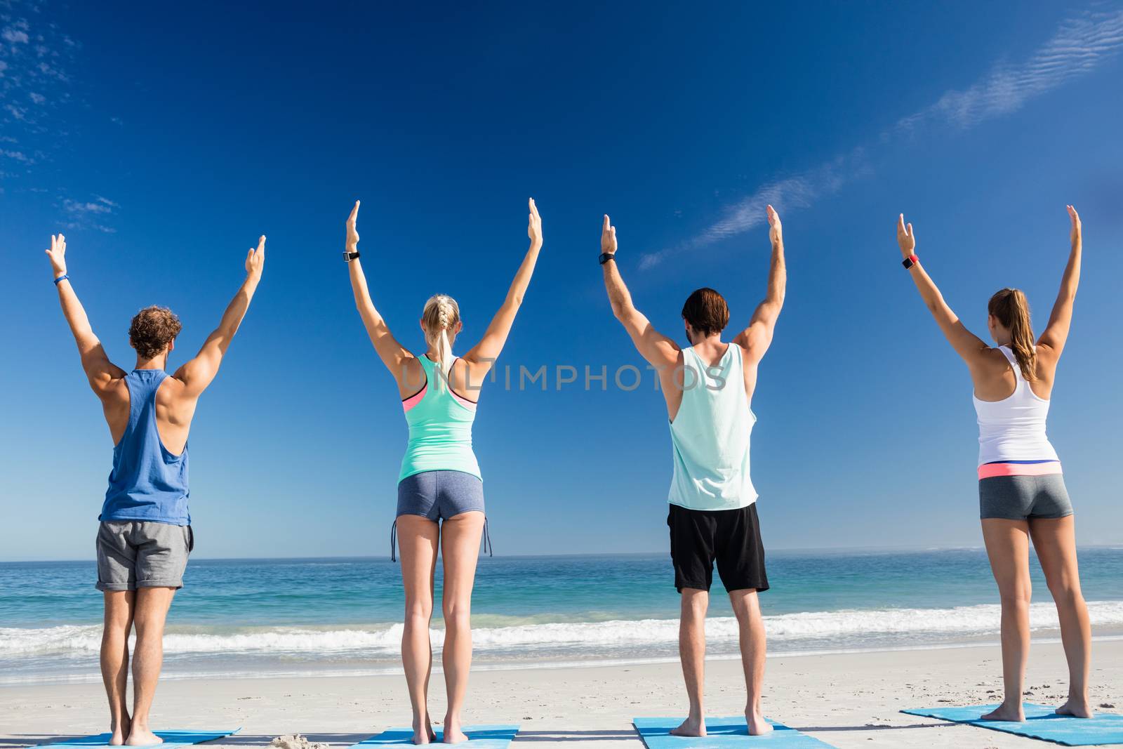 People doing yoga on the beach by Wavebreakmedia