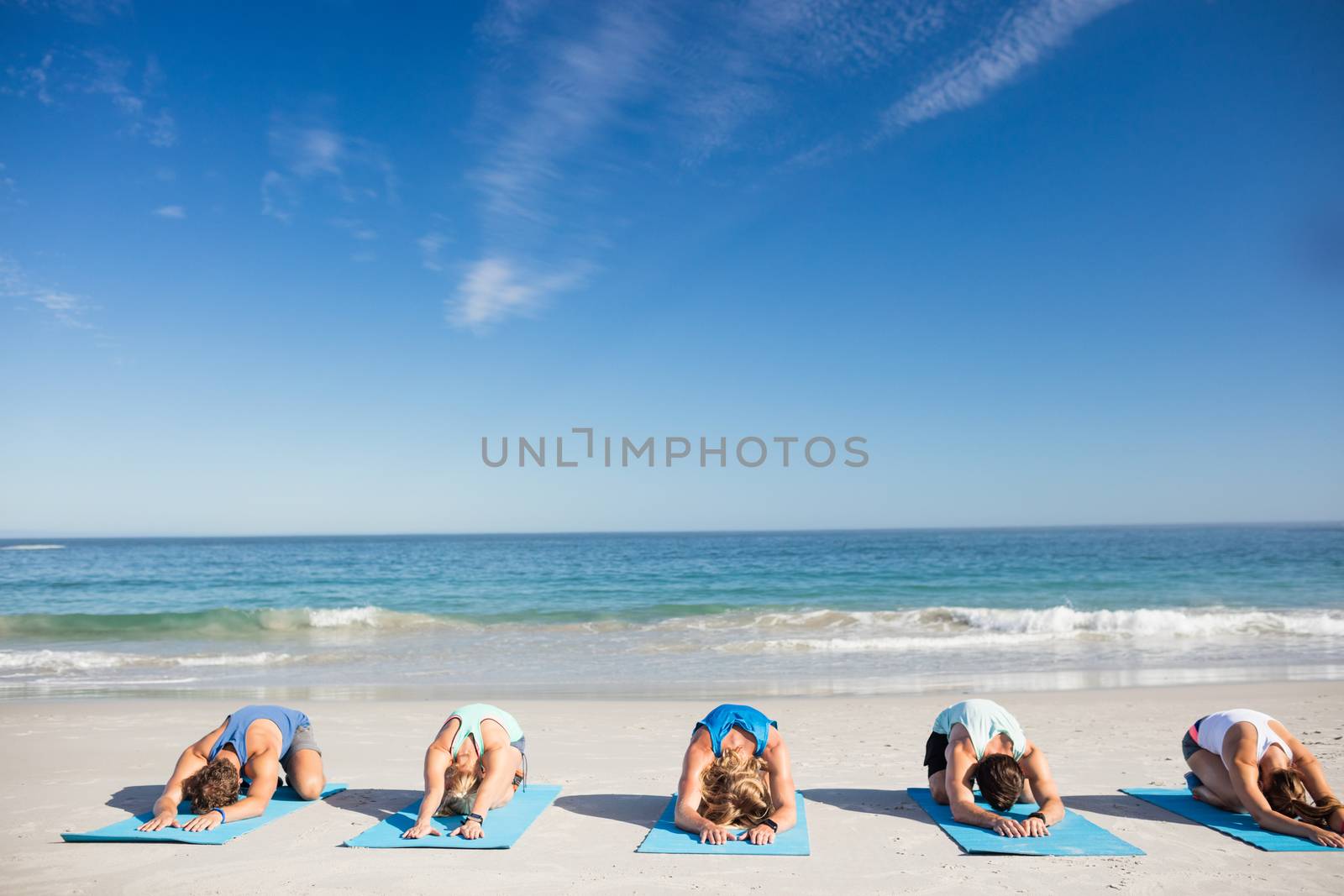 People doing yoga on the beach by Wavebreakmedia