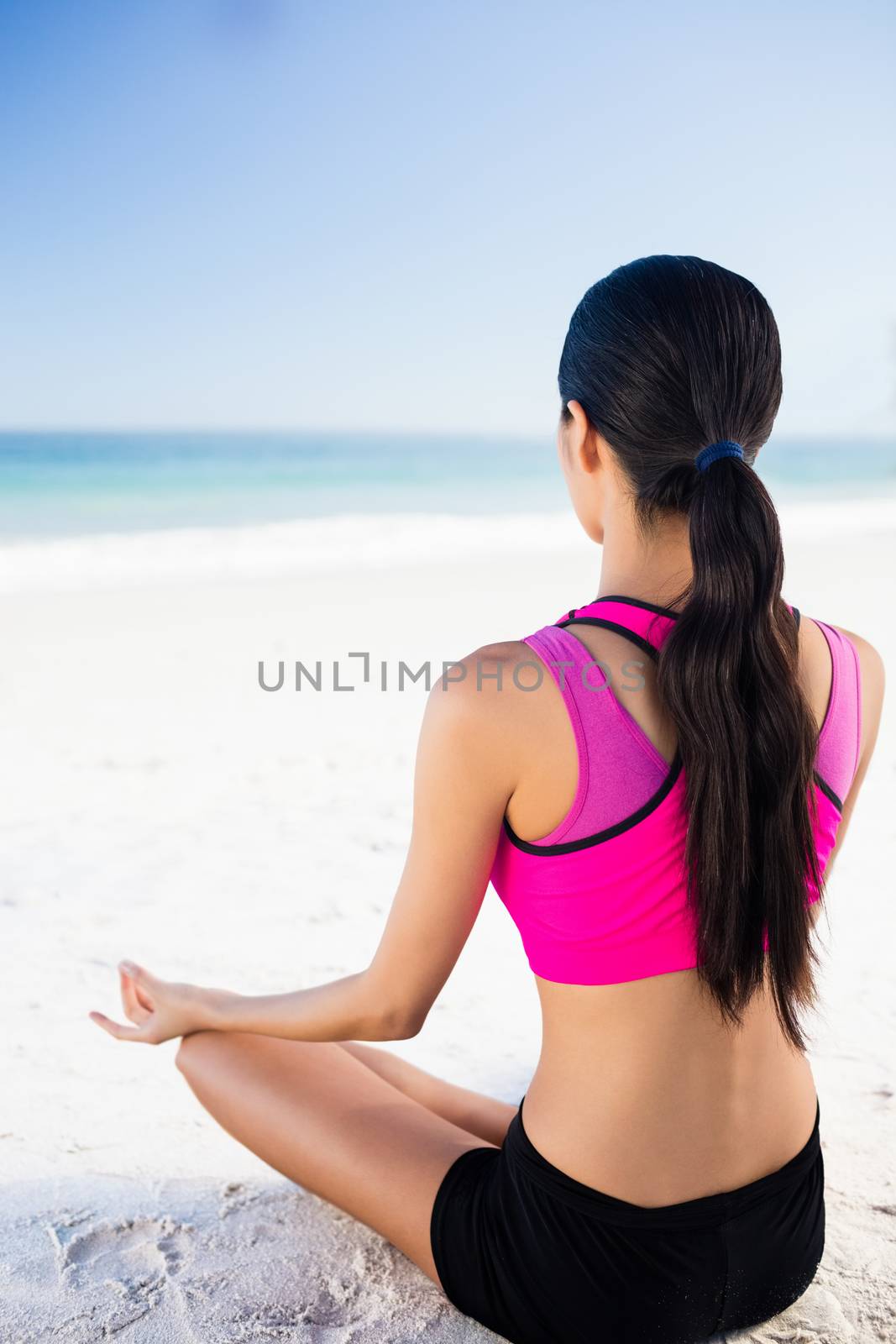 Woman doing yoga on the beach on a sunny day