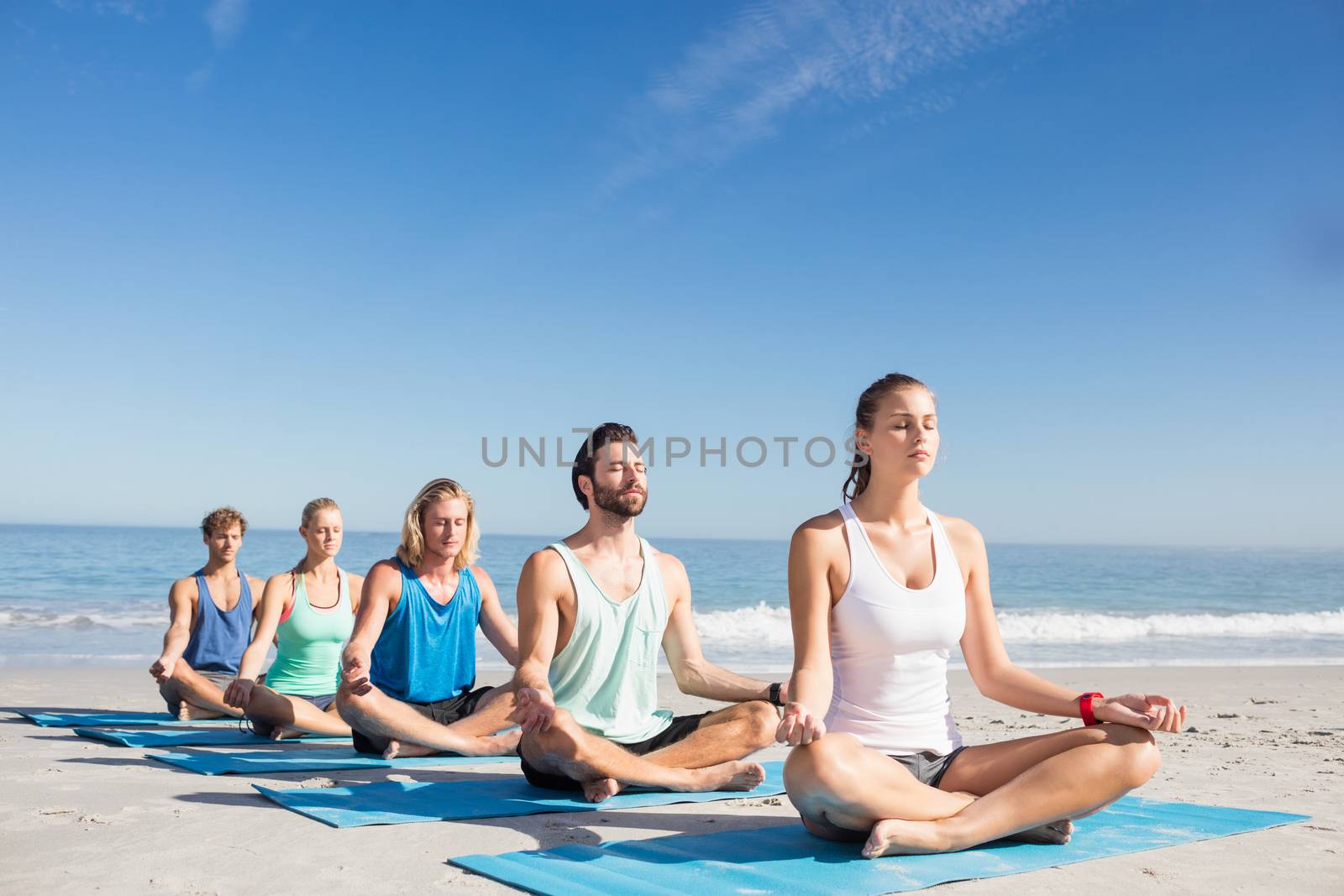 People doing yoga on the beach on a sunny day