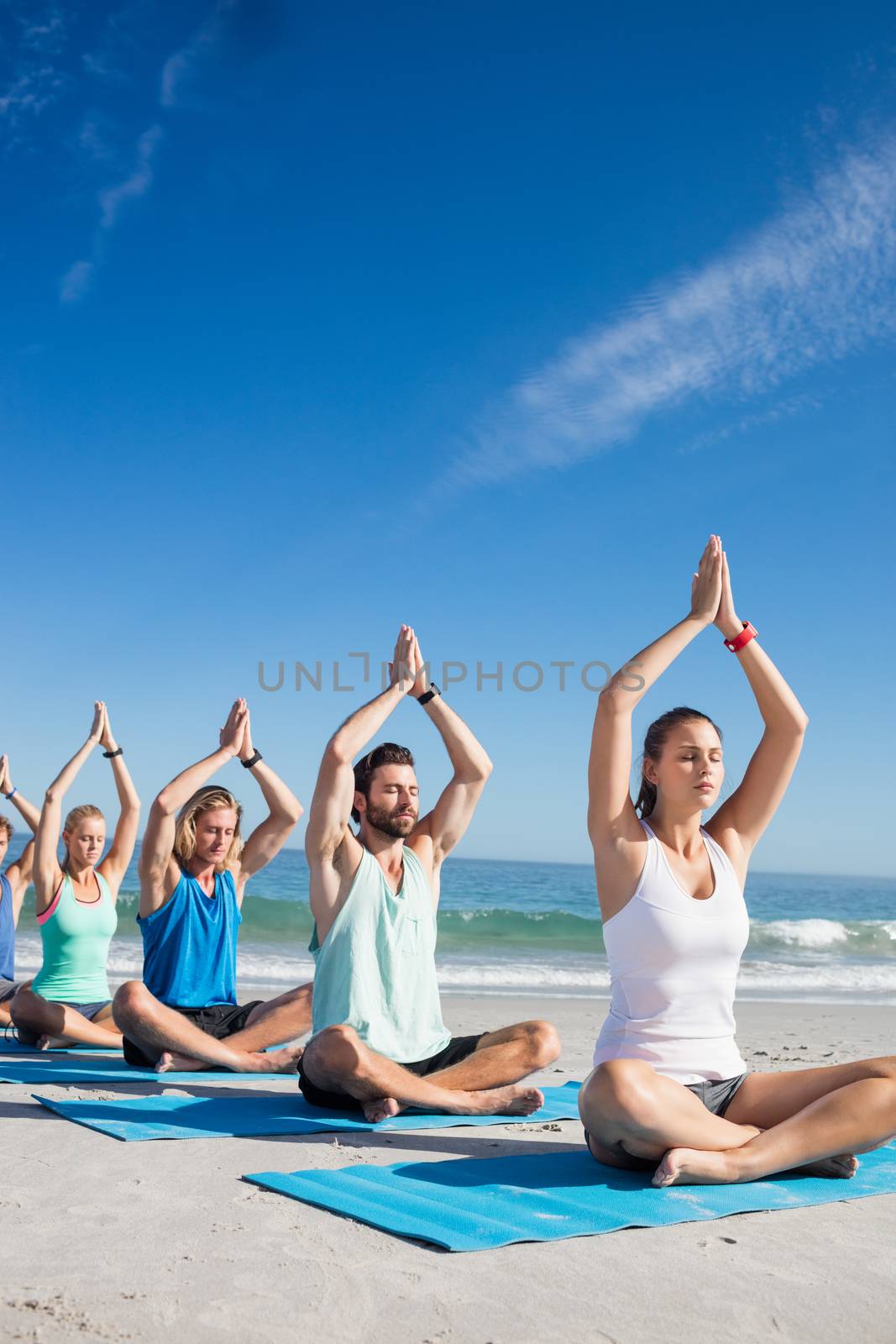 People doing yoga on the beach by Wavebreakmedia