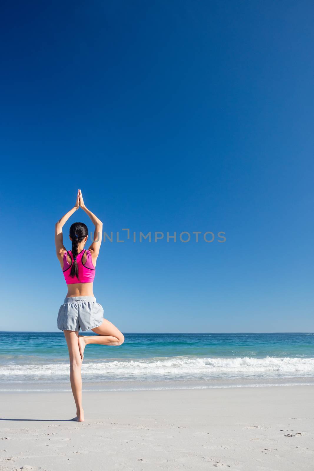 Woman doing yoga on the beach on a sunny day