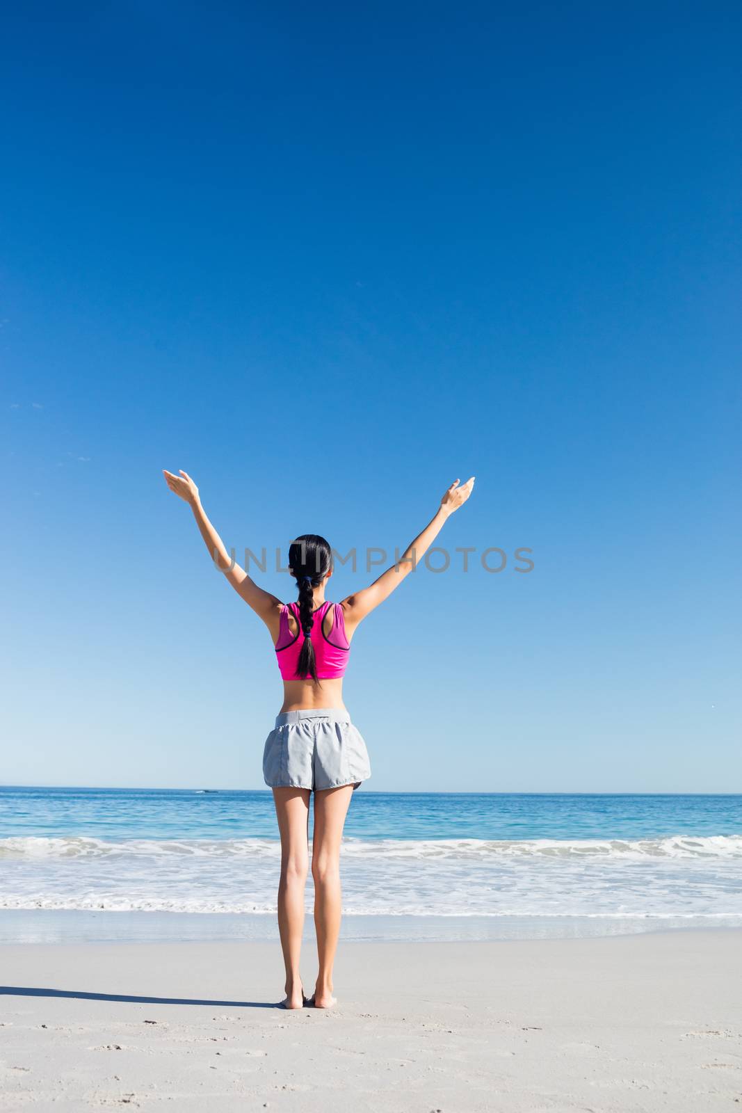Woman with hands up on the beach on a sunny day