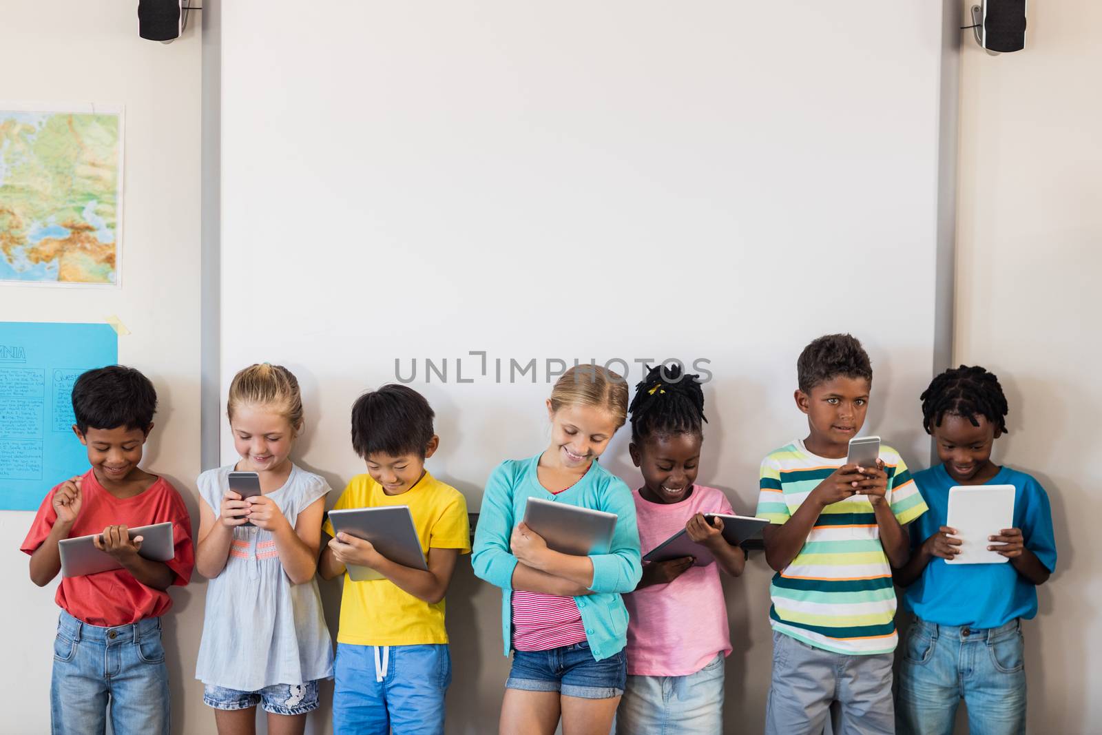 Pupils standing with technology by Wavebreakmedia
