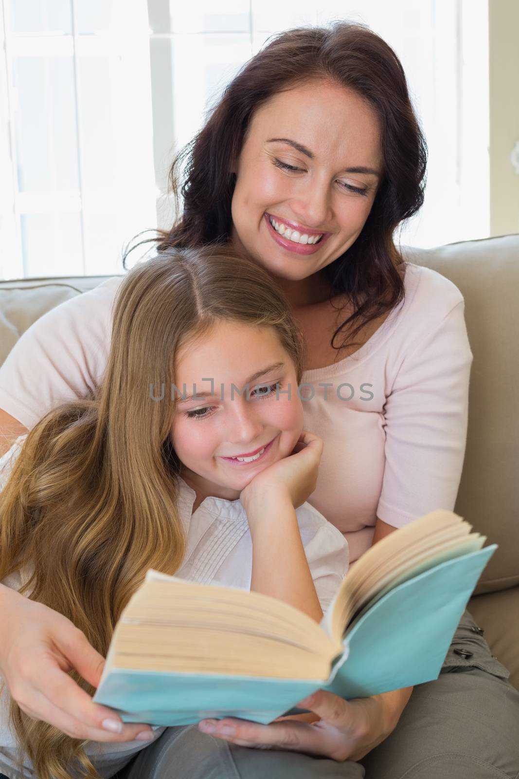 Happy woman and daughter reading story book together in house