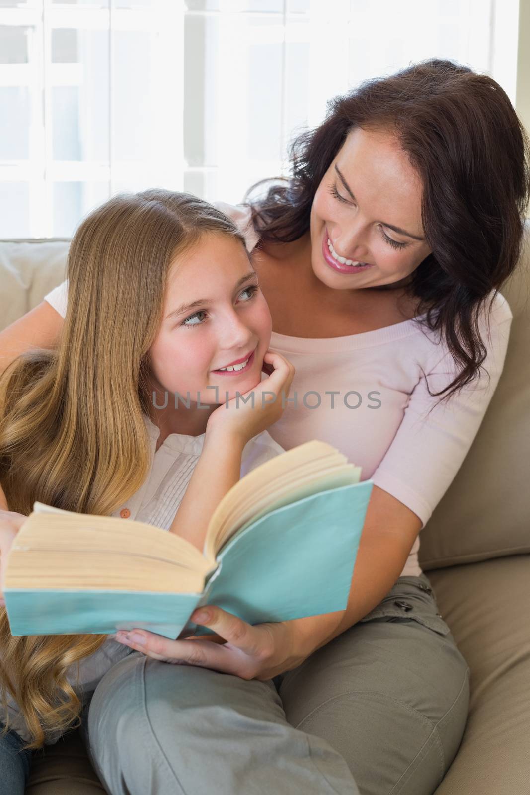 Happy mother and daughter with story book in house