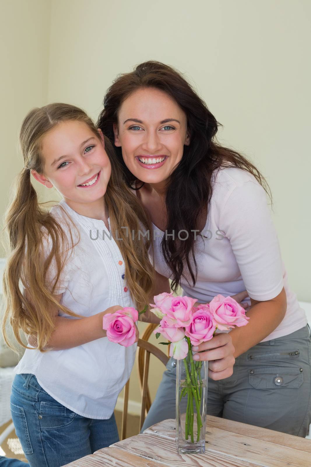 Mother and daughter arranging flowers in vase by Wavebreakmedia
