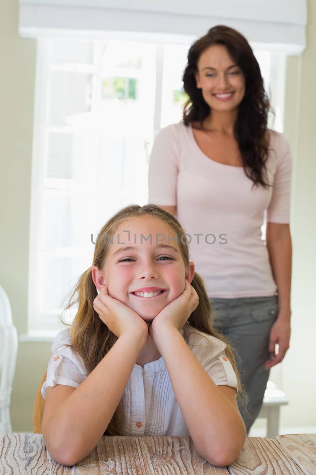 Portrait of cute girl smiling with mother standing in background at home