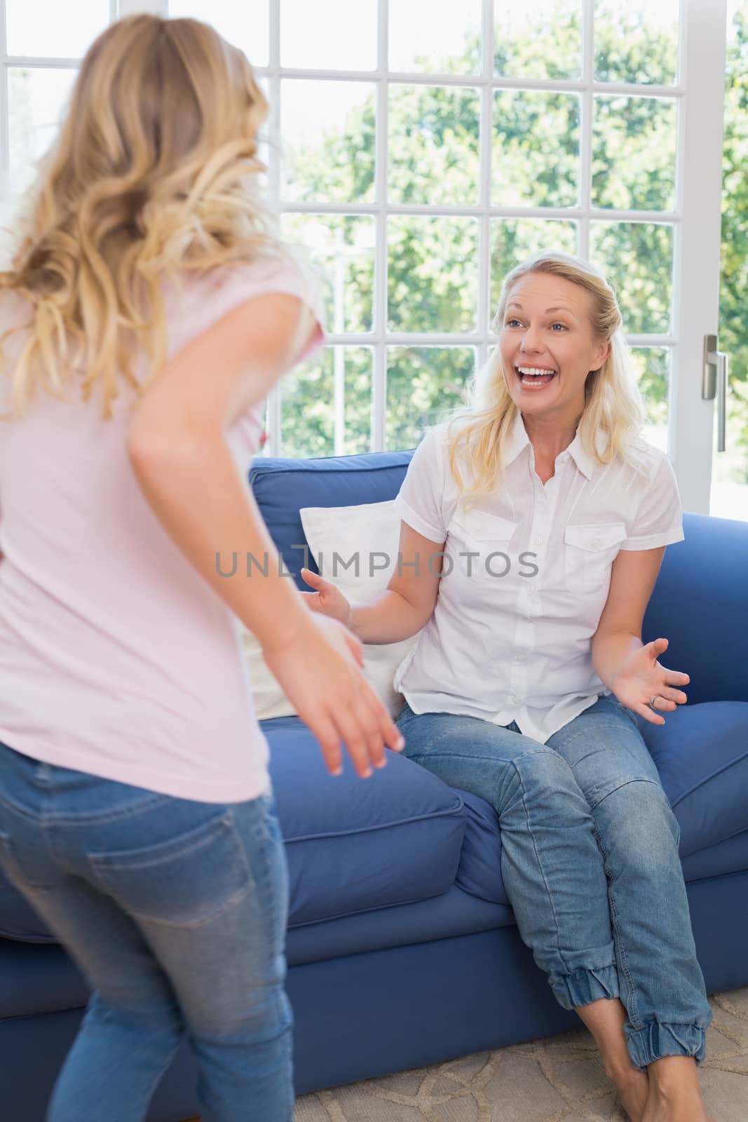 Excited mother looking at daughter in living room