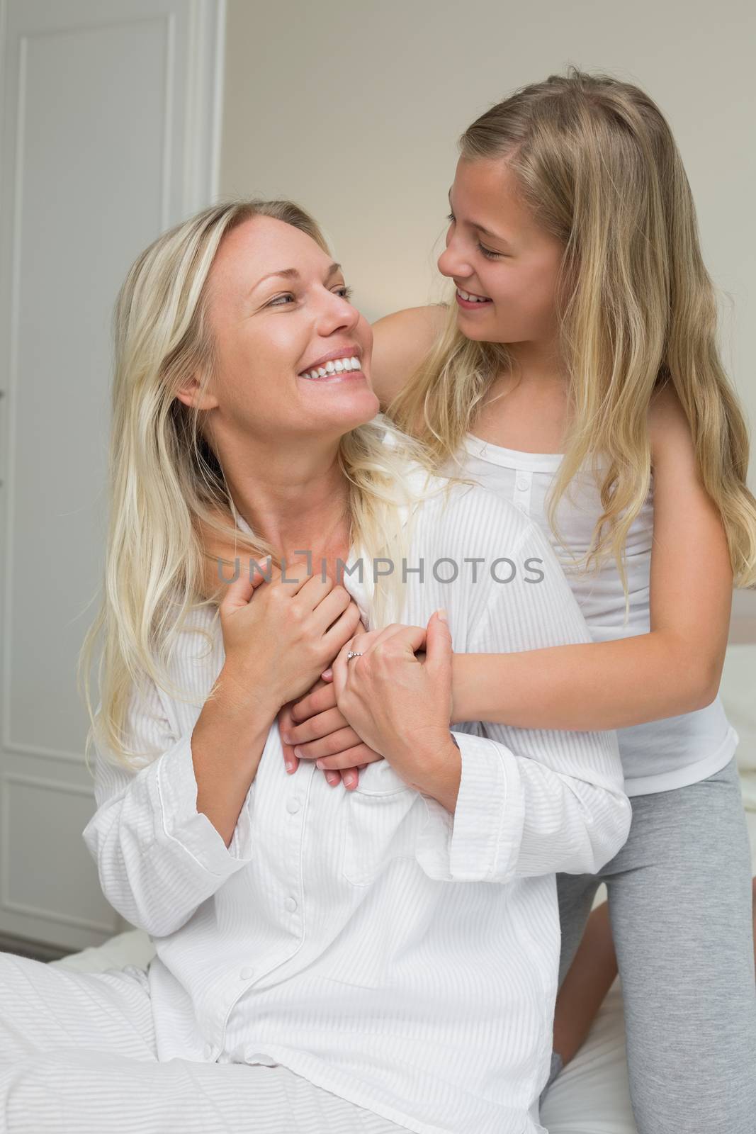 Happy mother and daughter looking at each other while sitting in bed