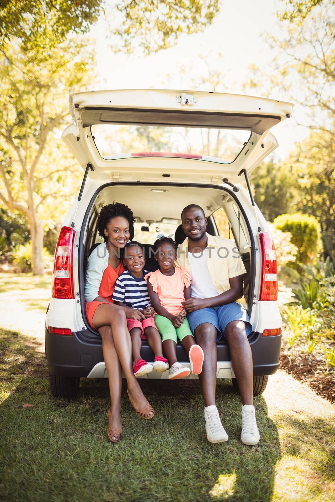 Happy family sitting on their car by Wavebreakmedia