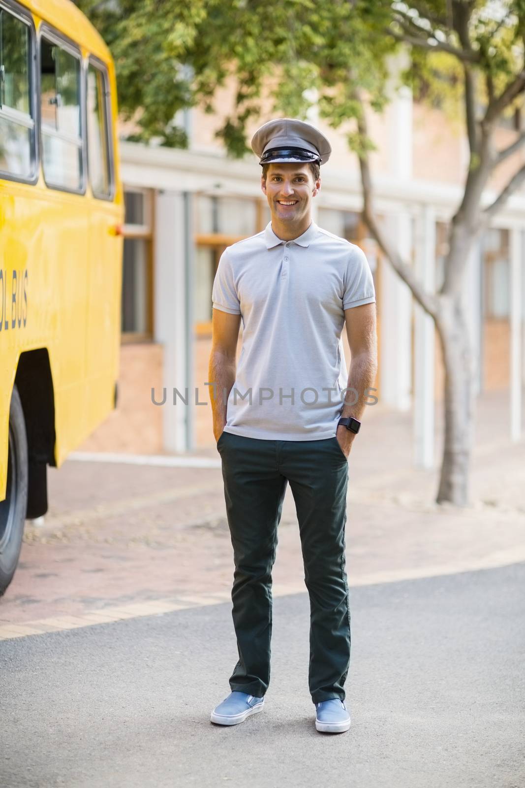 Portrait of smiling bus driver standing with hands in pocket in front of bus
