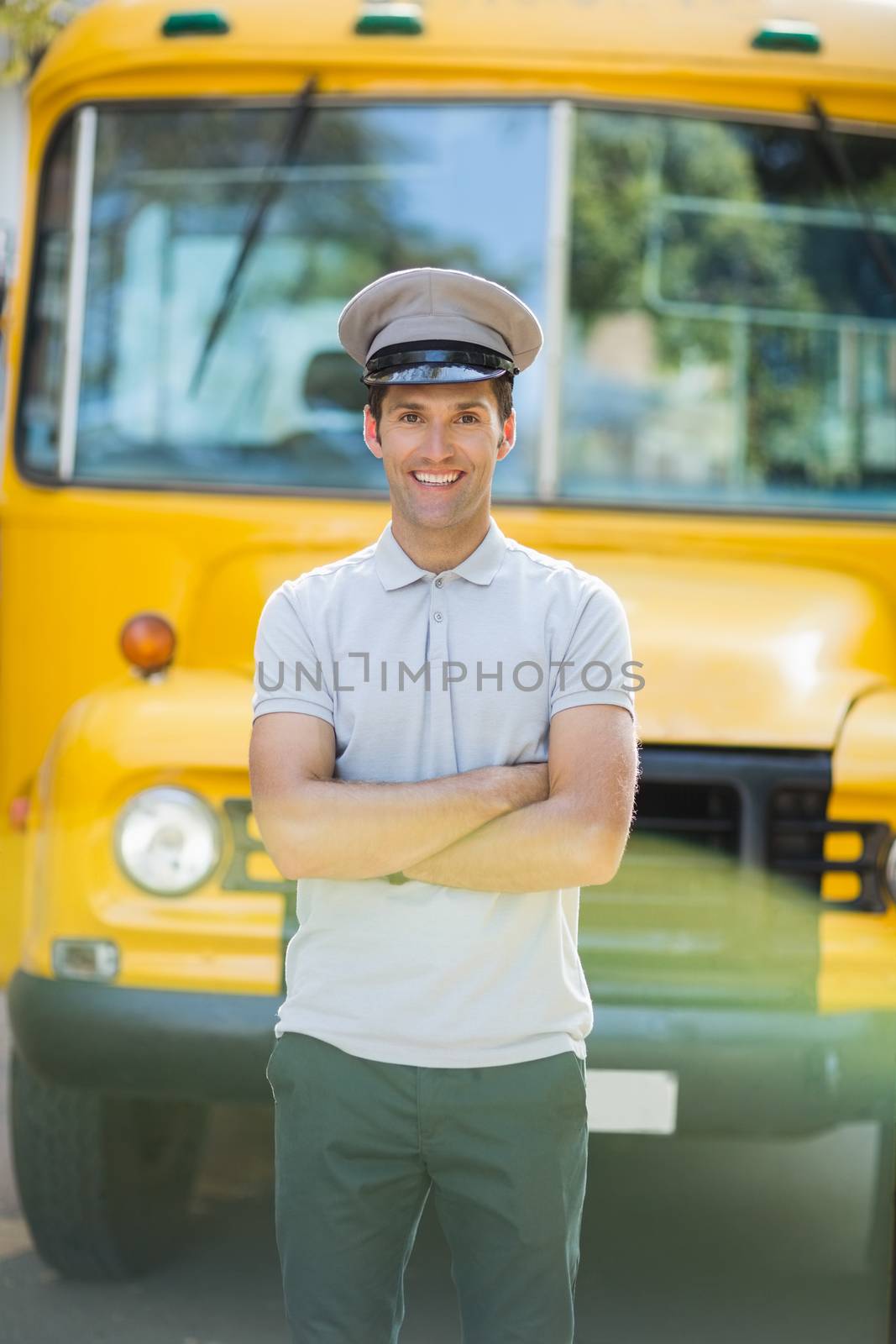Smiling bus driver standing with arms crossed in front of bus by Wavebreakmedia