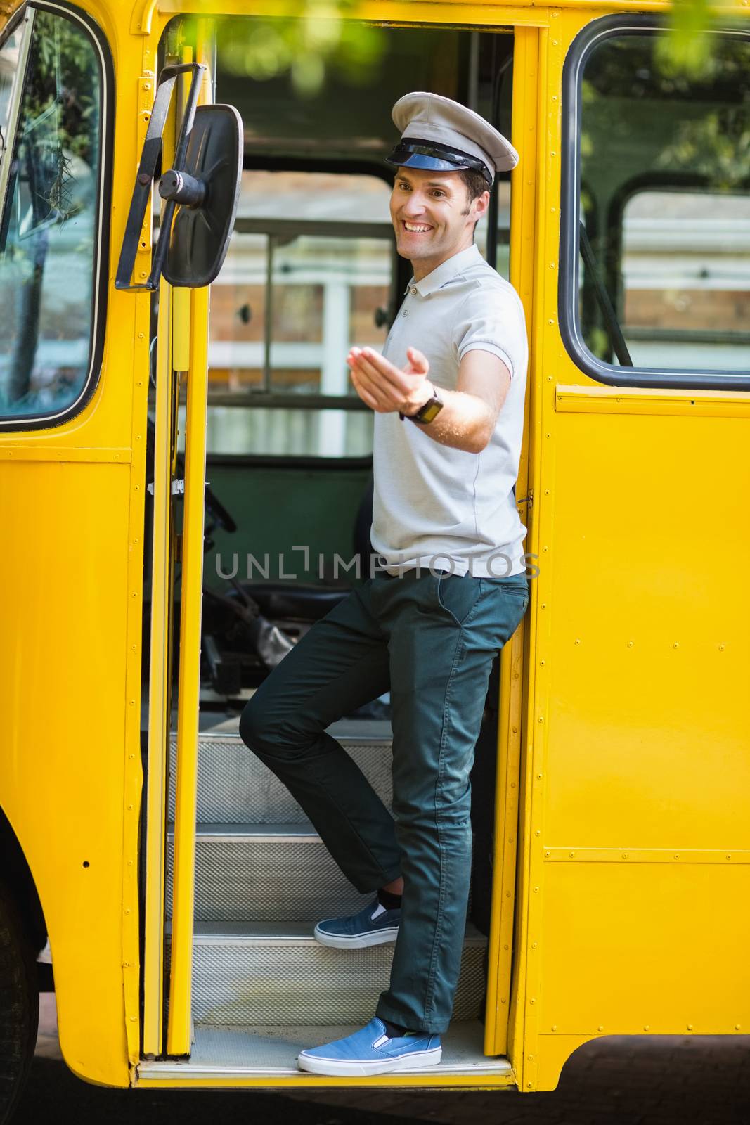 Smiling bus driver standing at the entrance of bus and gesturing