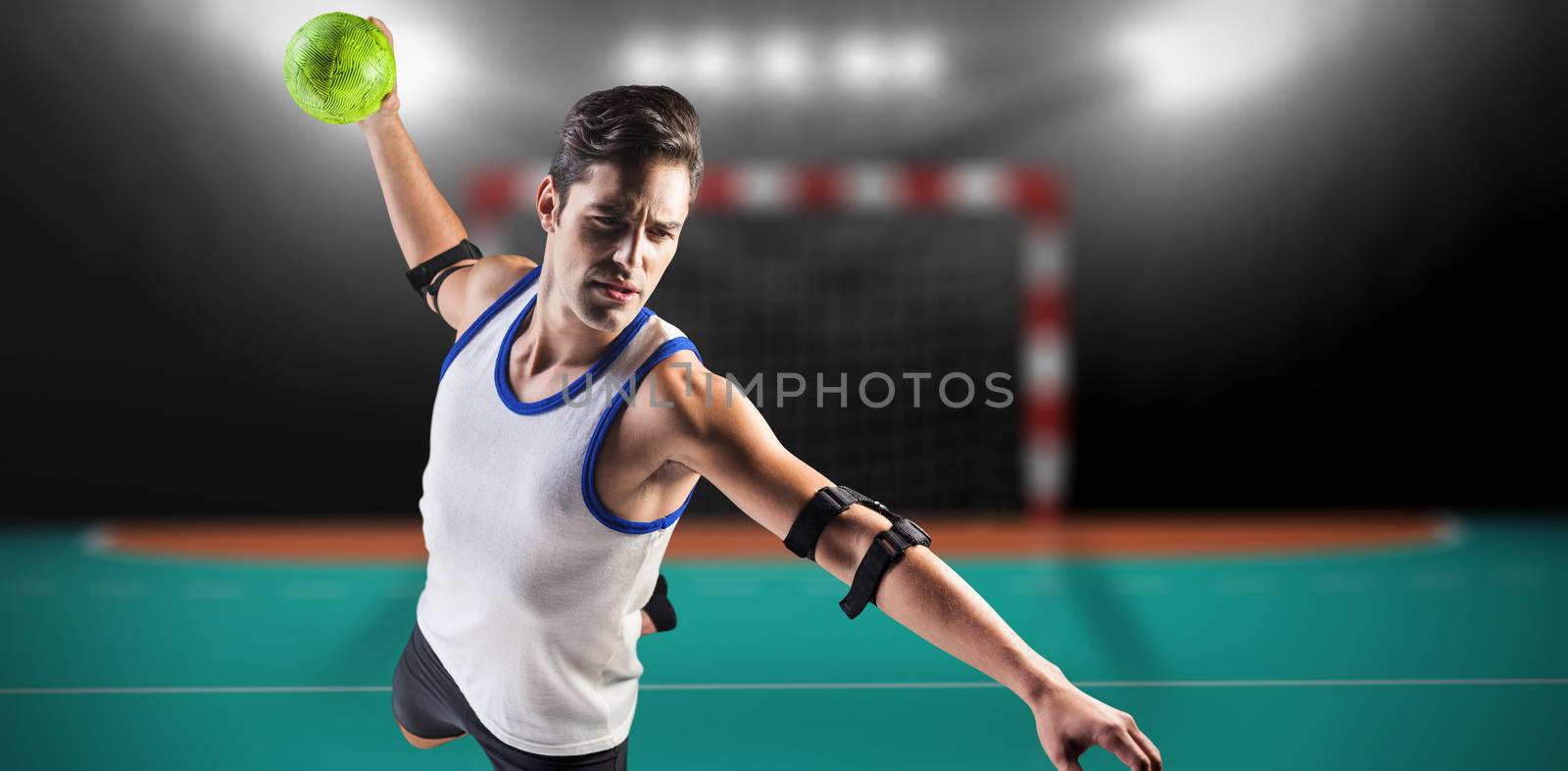 Confident athlete man throwing a ball  against handball field indoor 