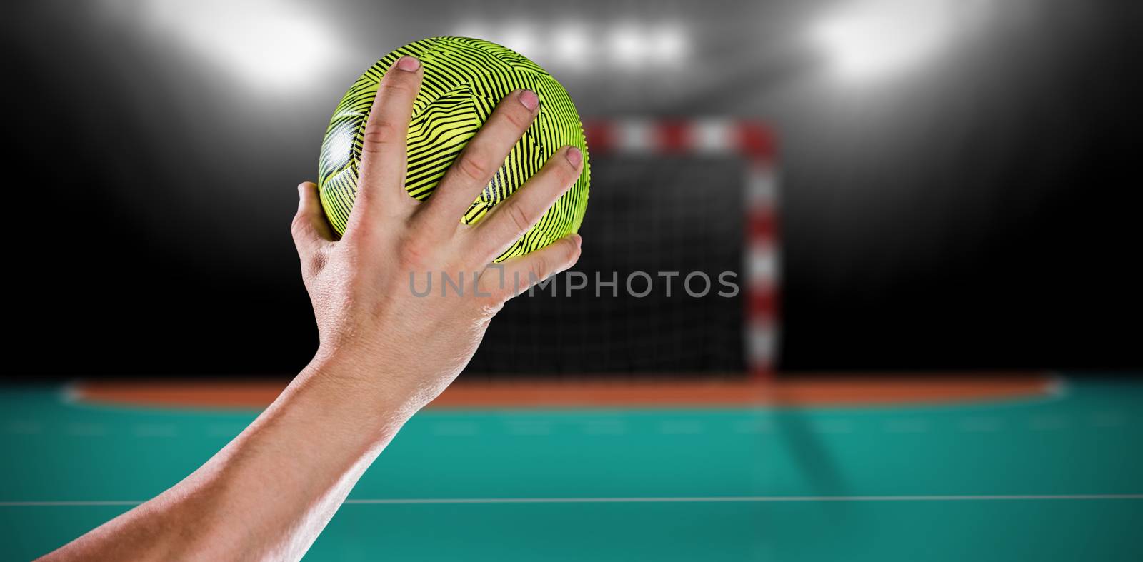 Sportsman holding a ball against handball field indoor 