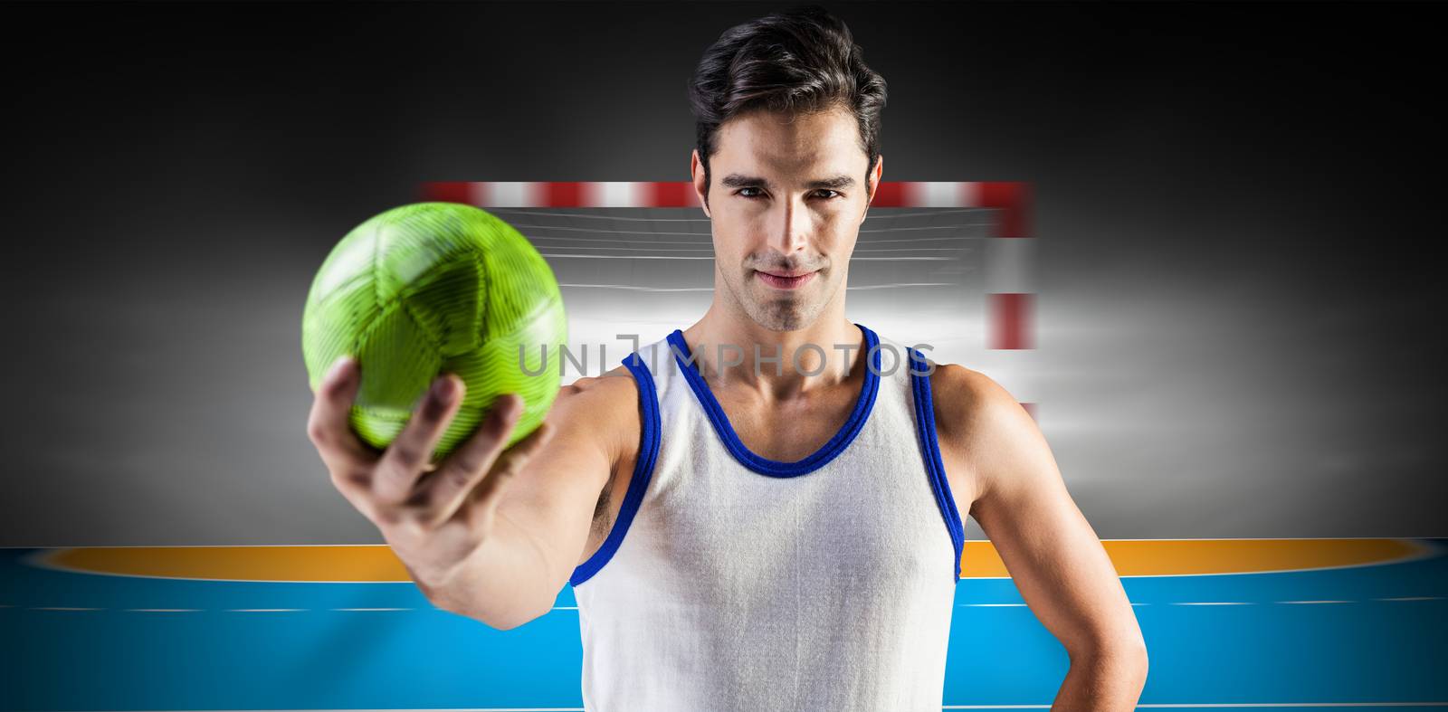 Portrait of happy male athlete holding a ball against handball field indoor 