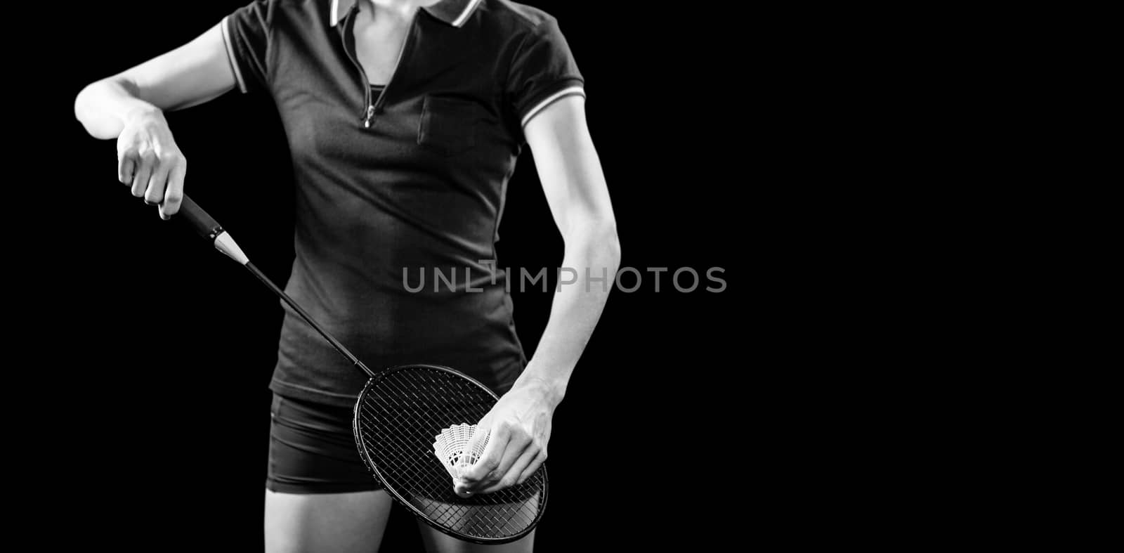 Badminton player holding a racquet ready to serve on black background