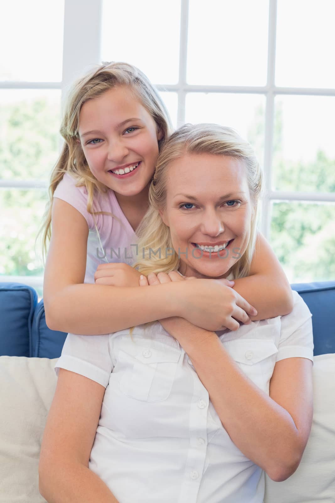 Portrait of cute girl embracing mother from behind in living room