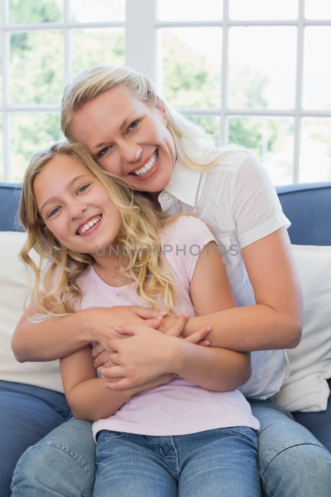 Happy mother embracing daughter on sofa by Wavebreakmedia