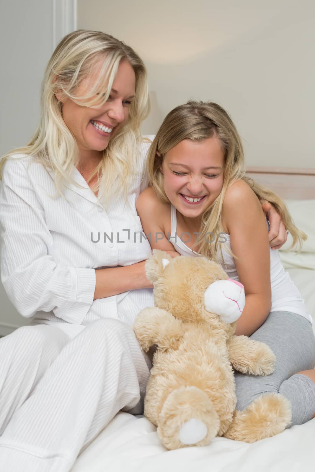 Mother tickling daughter in bed by Wavebreakmedia