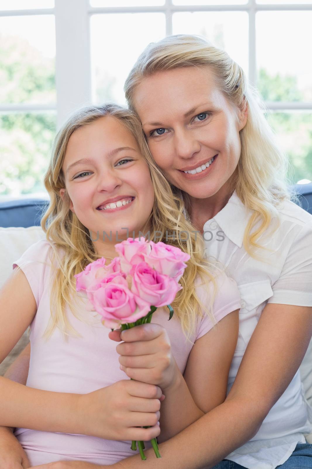 Happy mother and daughter with rose bouquet in house