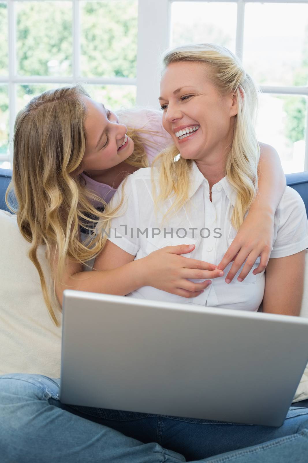 Woman with laptop looking at daughter by Wavebreakmedia