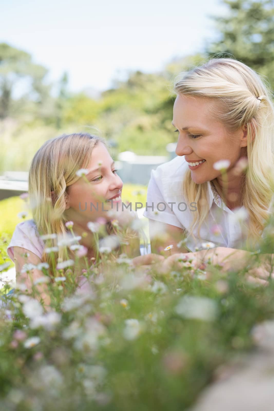 Smiling mother and daughter looking at each other while lying in park