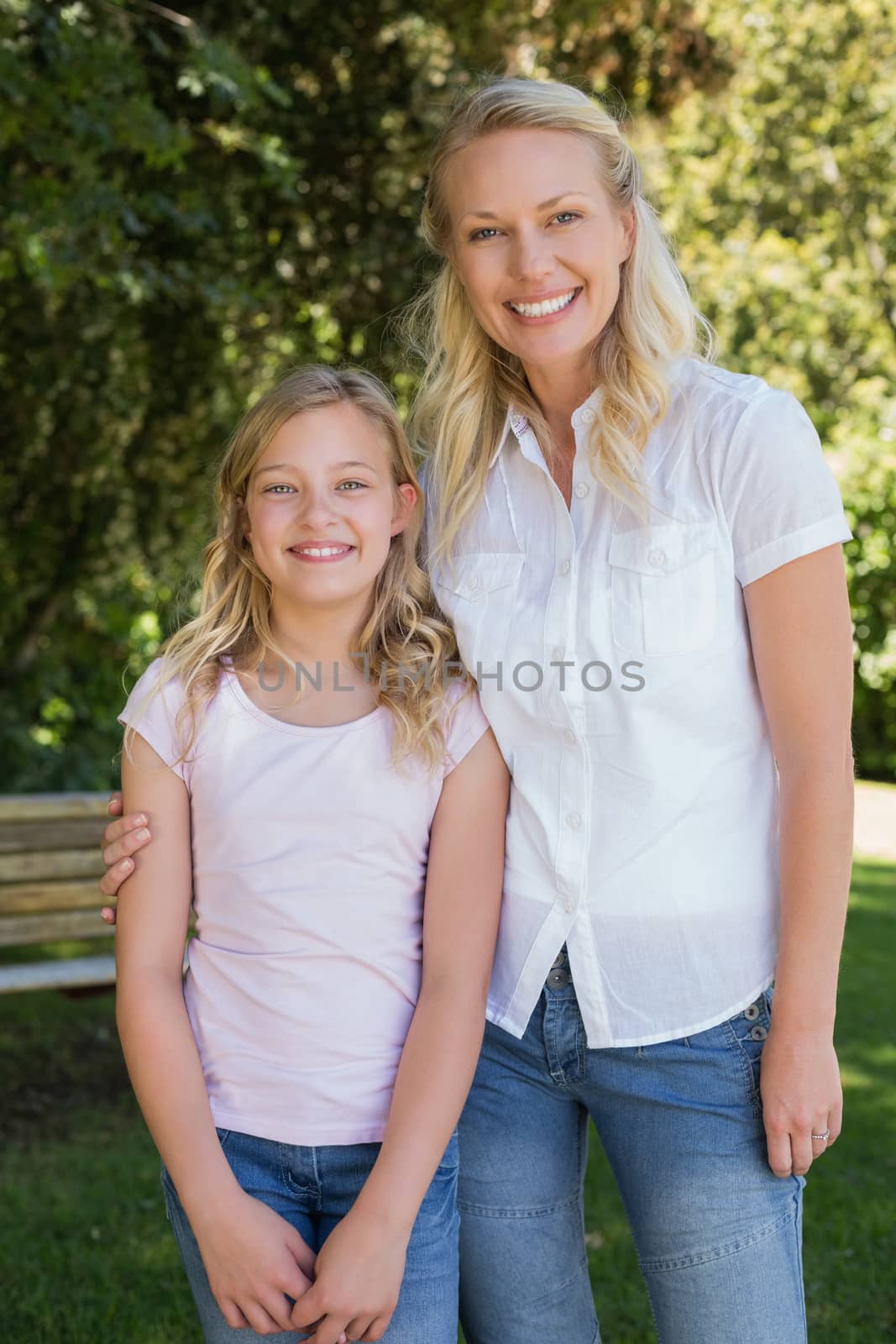 Portrait of mother with arm around daughter standing in park