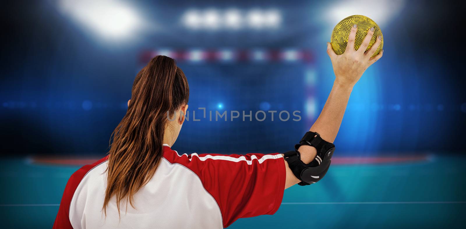 Sportswoman holding a ball against handball field indoor 