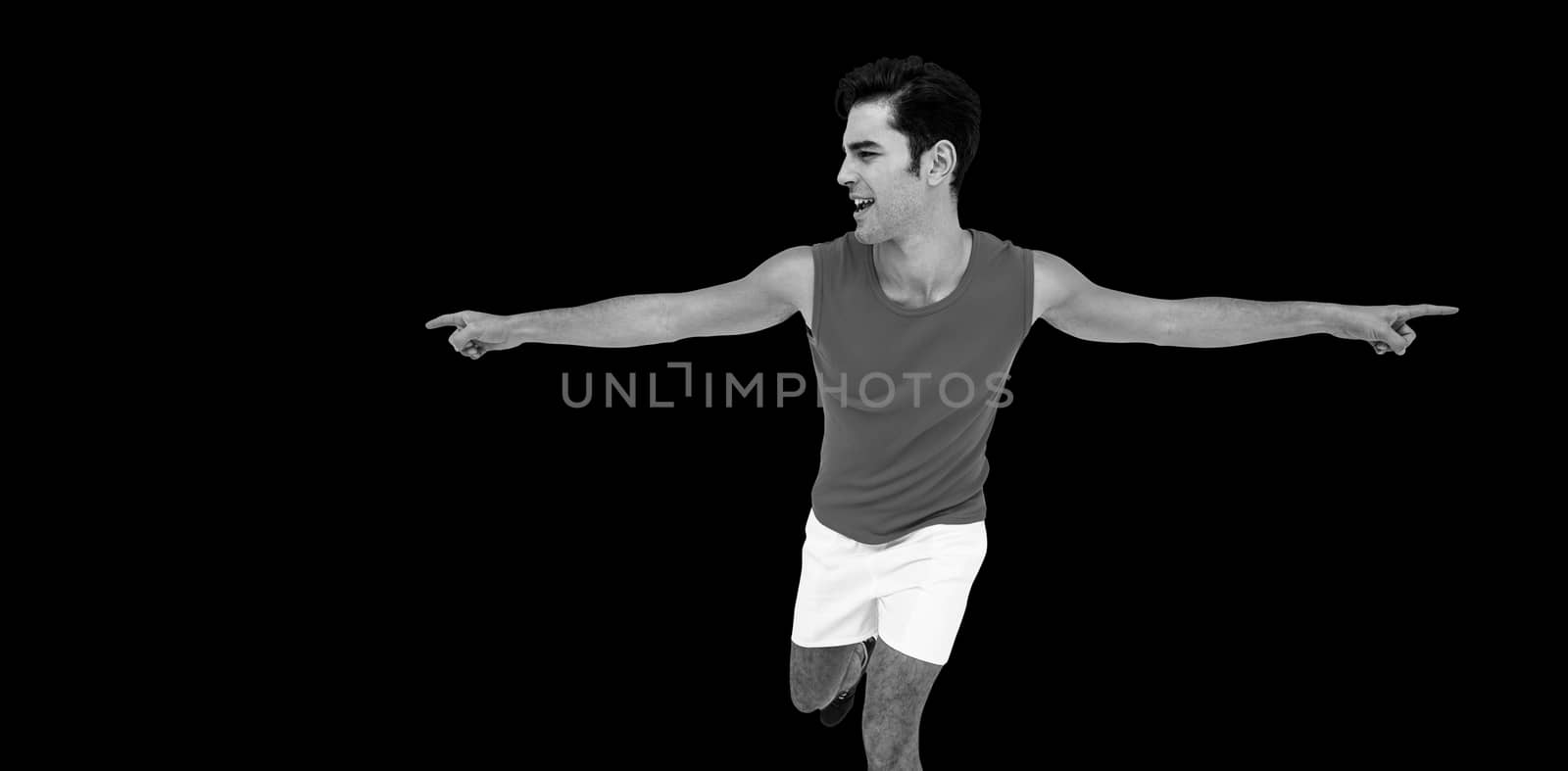 Excited male athlete with arms outstretched after victory on black background