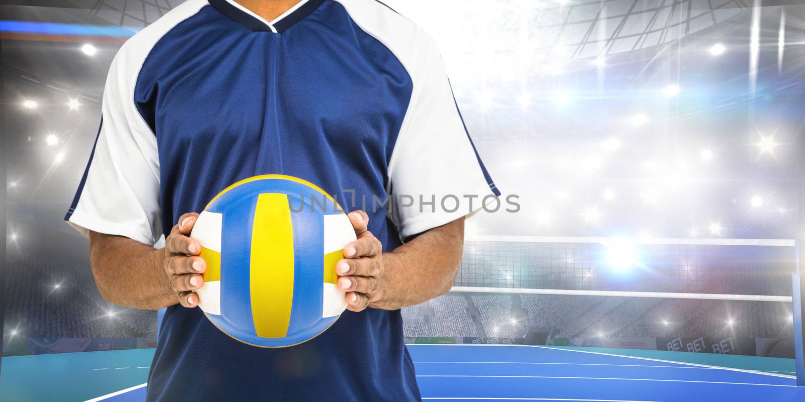 Mid-section of sportsman holding a volleyball against view of a volleyball field