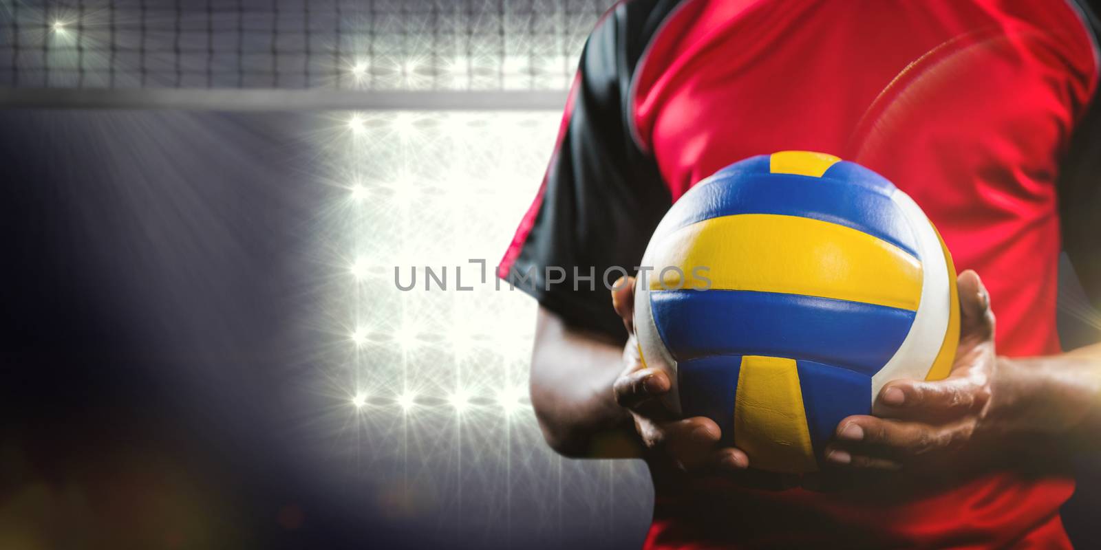 Mid-section of sportsman holding a volleyball against view of lighting