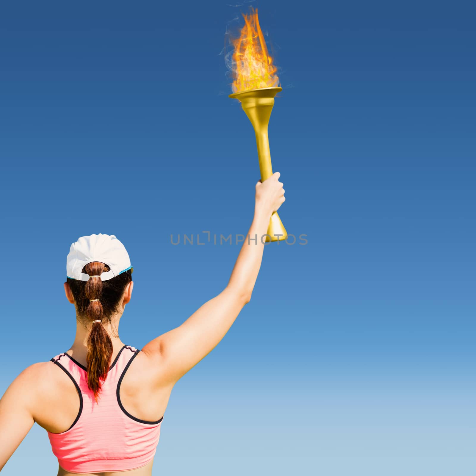 Rear view of sportswoman raising a cup  against blue sky