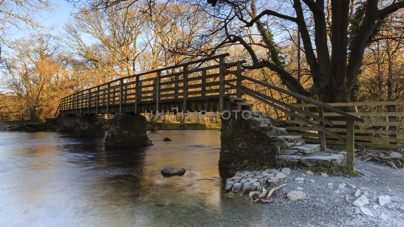 A wooden footbridge over a river between Grasmere and Rydal Water in the English Lake District national park.