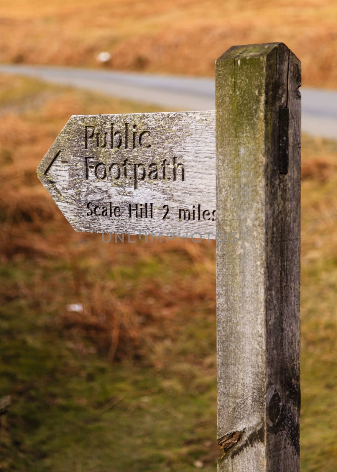 A wooden signpost marking a public footpath close to Crummock Water in the English Lake District national park.