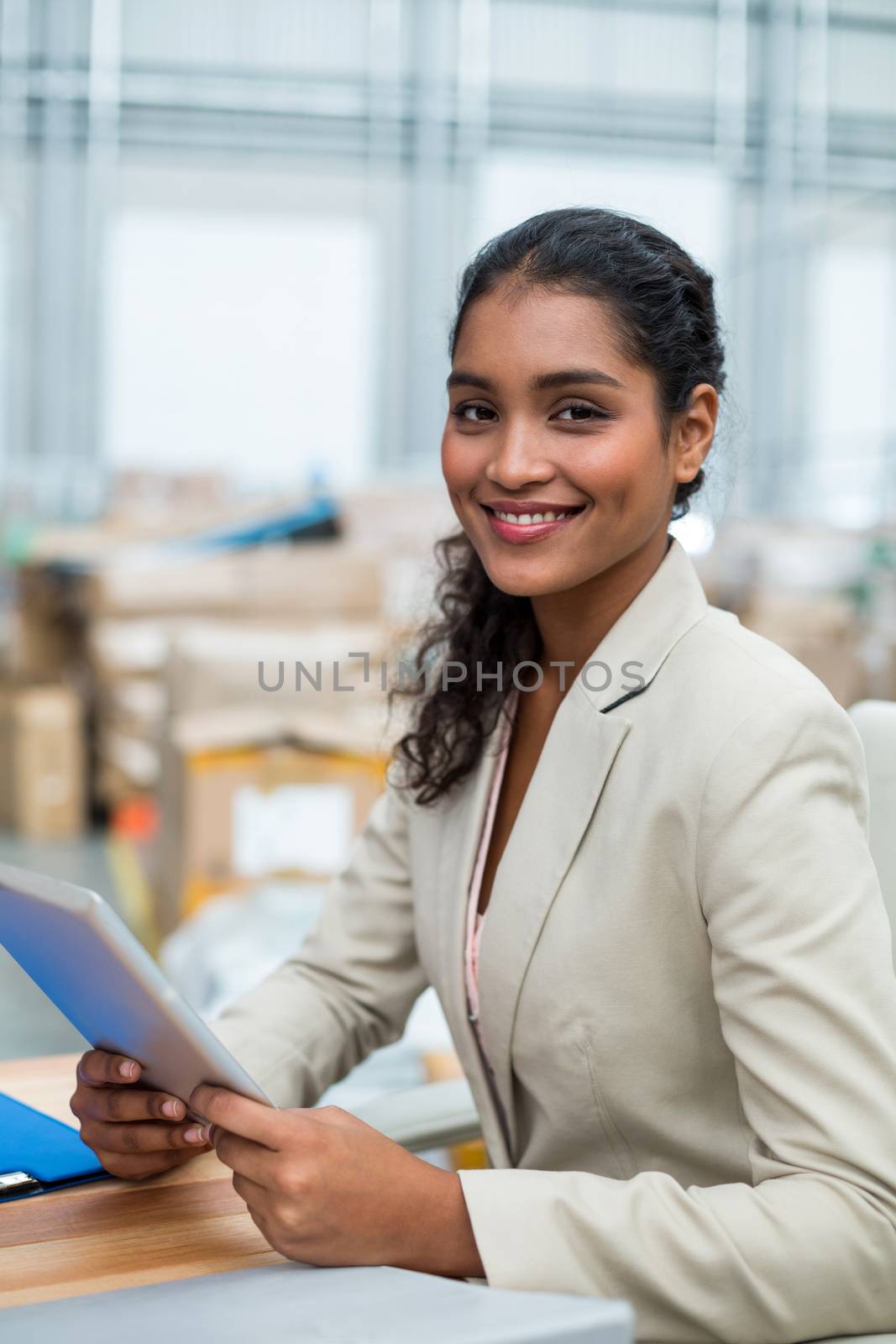 Portrait of manager is smiling and holding a tablet in a warehouse