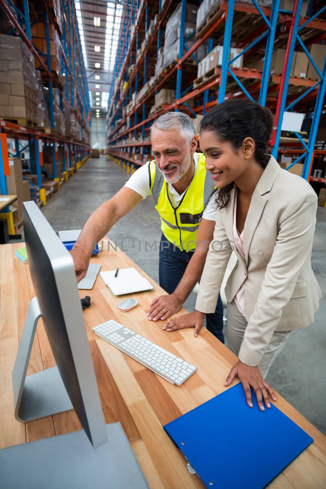 Side view of worker team is looking a computer and smiling in a warehouse