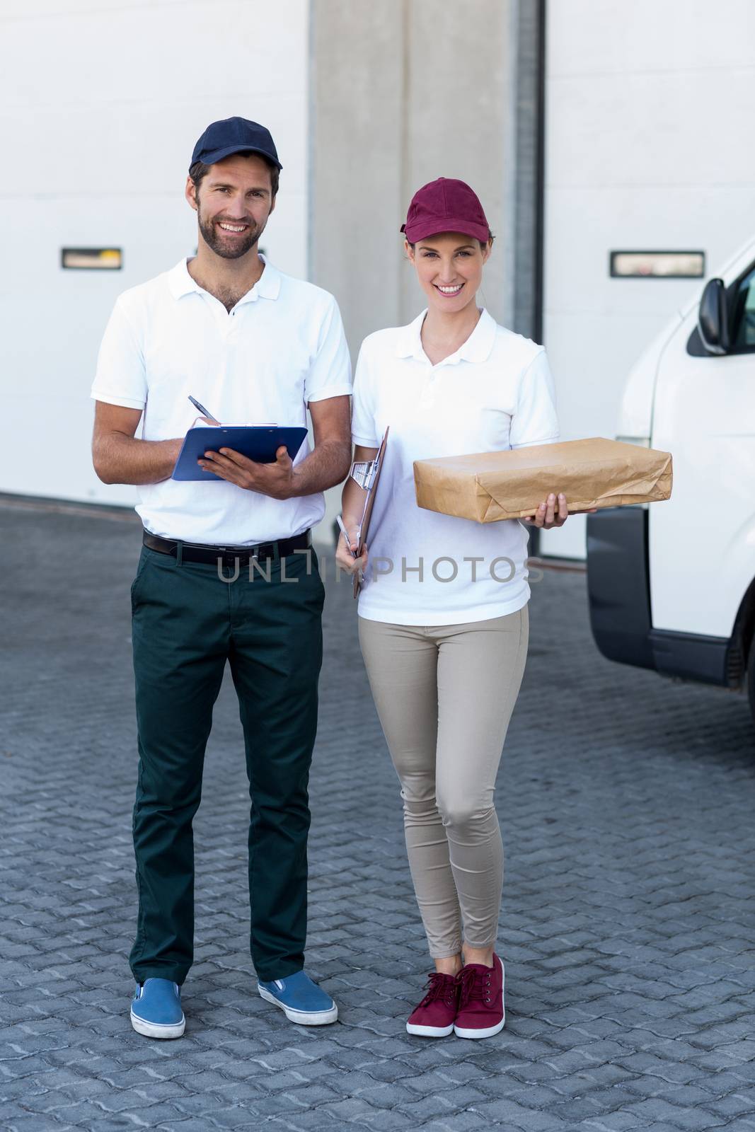 Delivery people are posing and holding goods in front of a warehouse