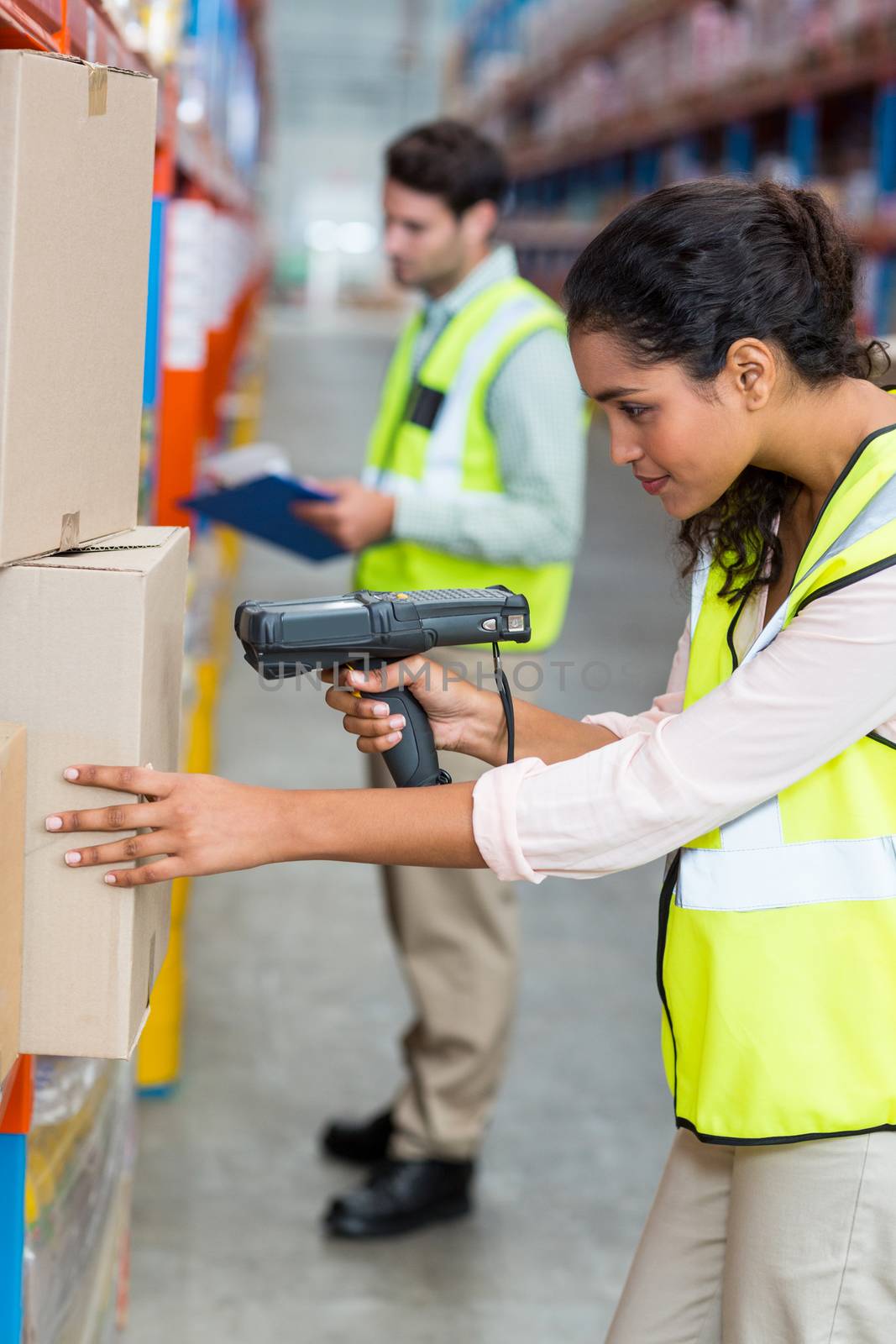 Focus of serious worker is working on cardboard boxes in a warehouse