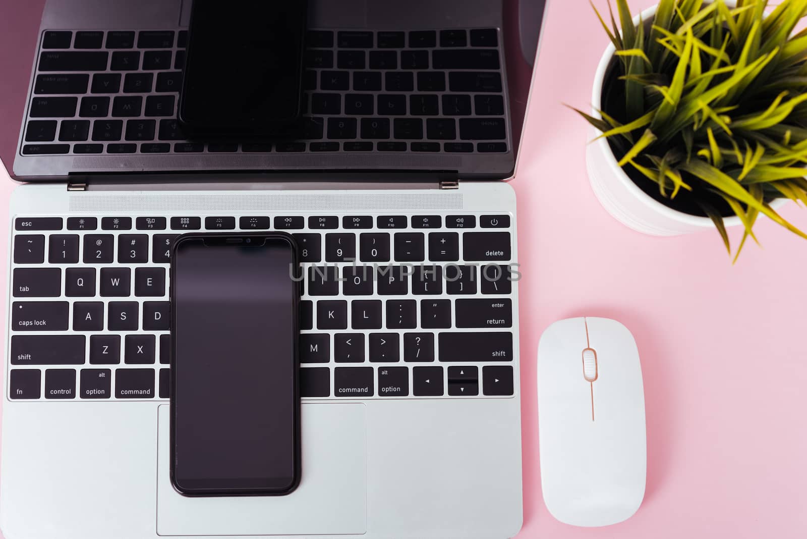 Top view of modern technology smart phone mobile and computer laptop on pink background with copy space