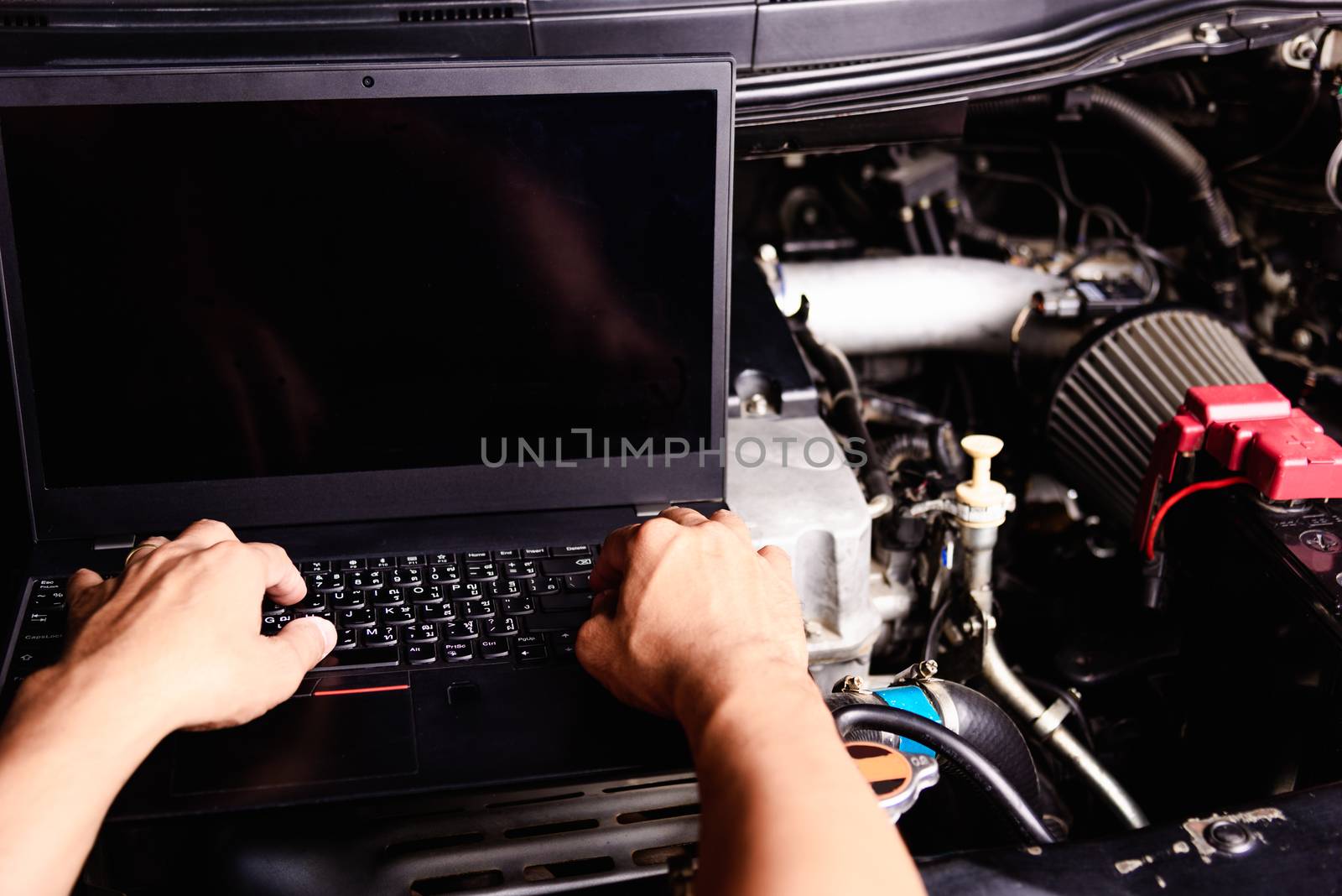 Professional car repair or maintenance mechanic engine working service with laptop computer at workshop