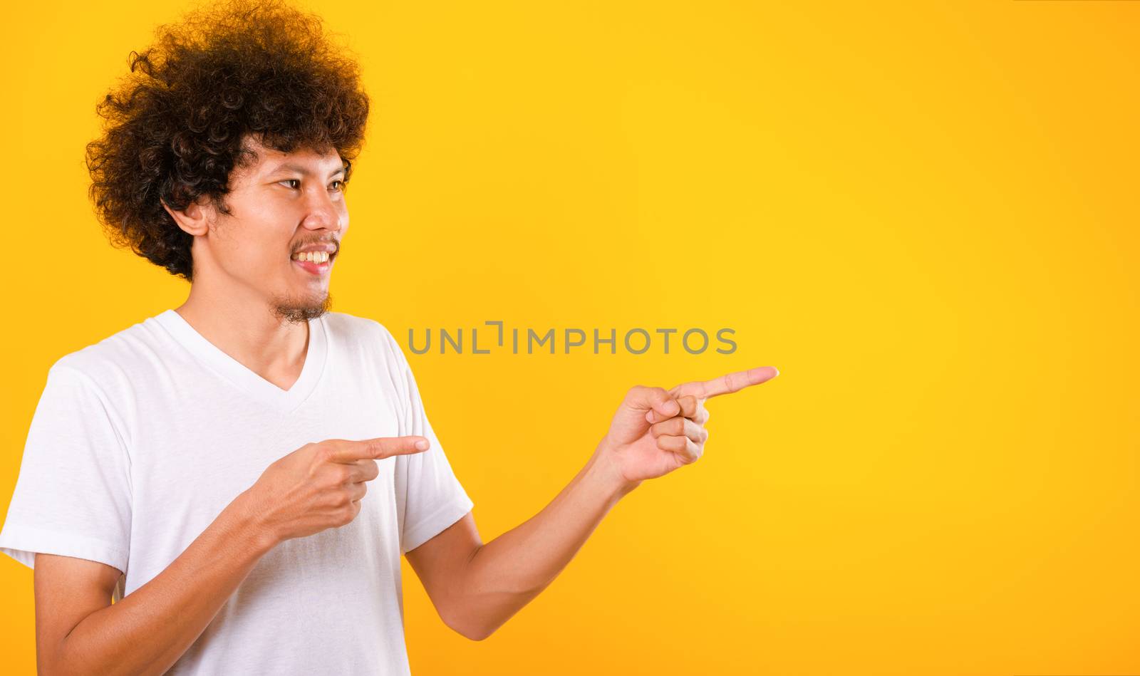 Asian Portrait happy young man curly hair pointing fingers away  by Sorapop