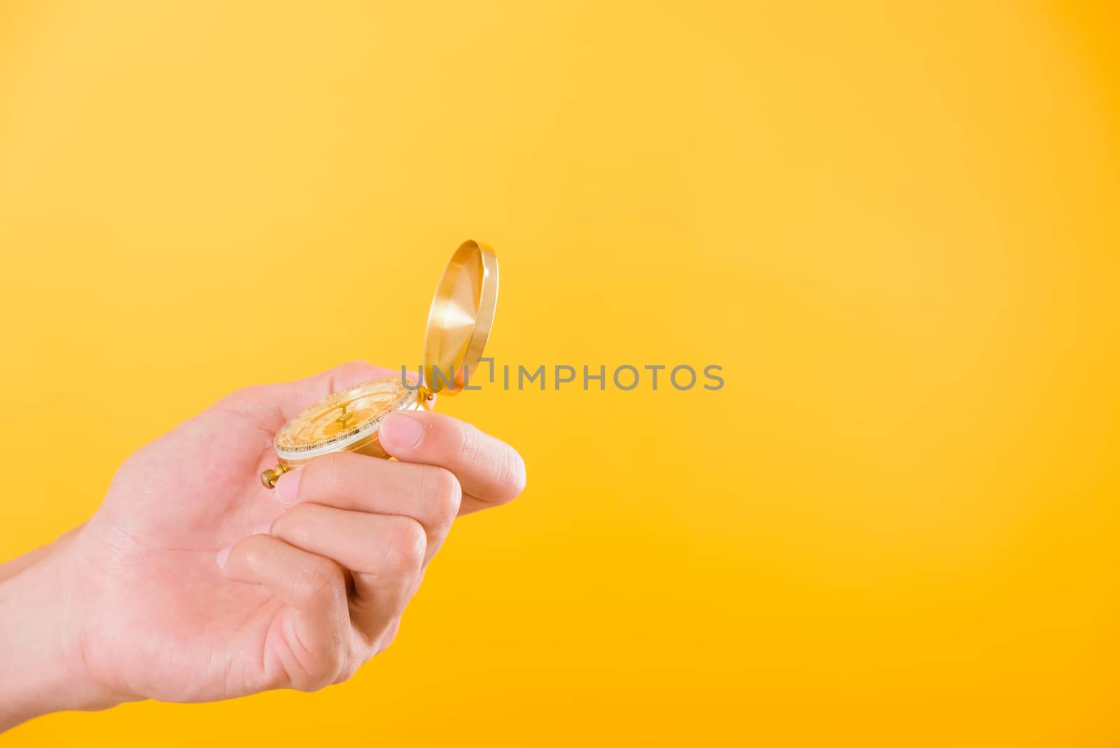 Hand holding antique brass compass isolated by Sorapop