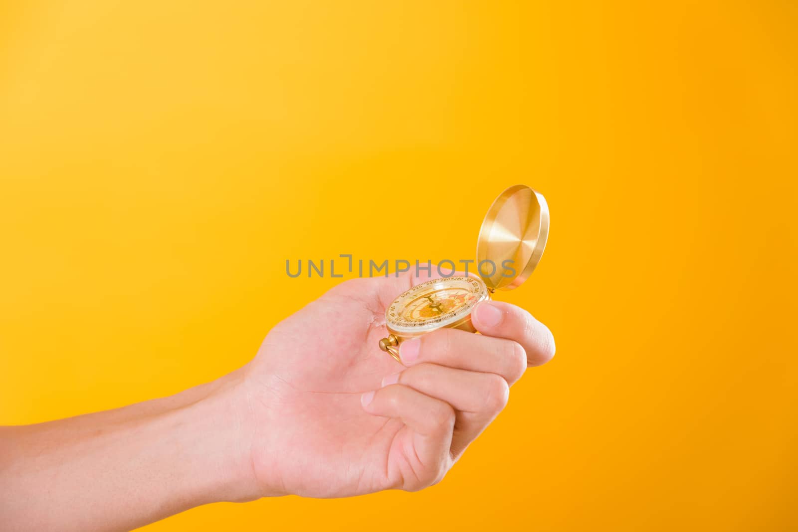 Hand holding antique brass compass isolated by Sorapop