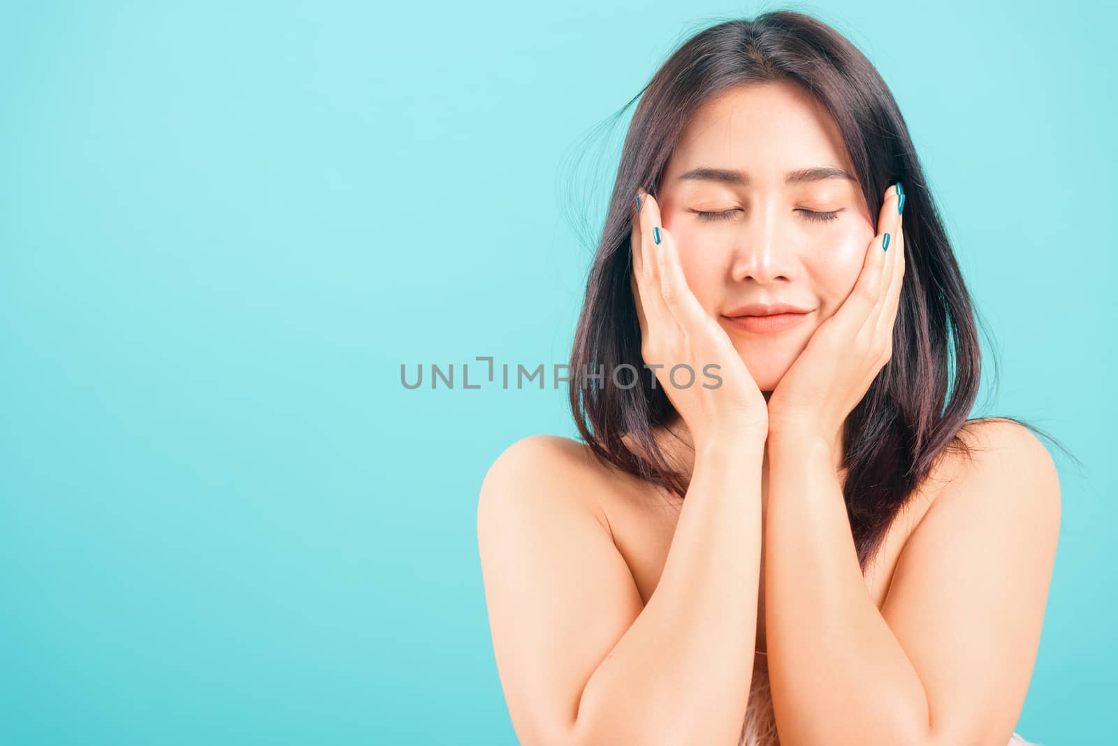 Smiling face Asian beautiful woman her touching face skin care on blue background, with copy space for text