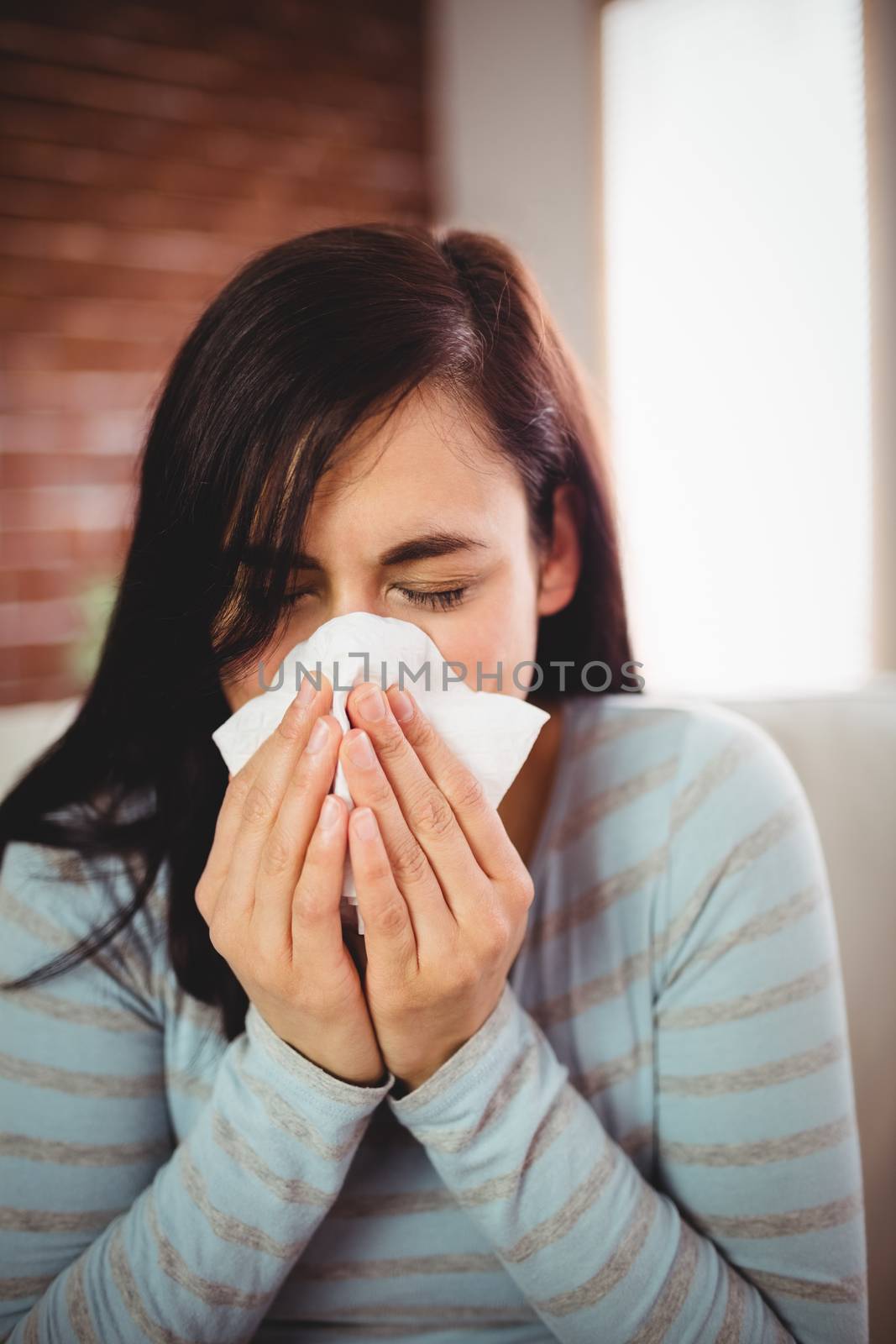 Woman sneezing at home by Wavebreakmedia