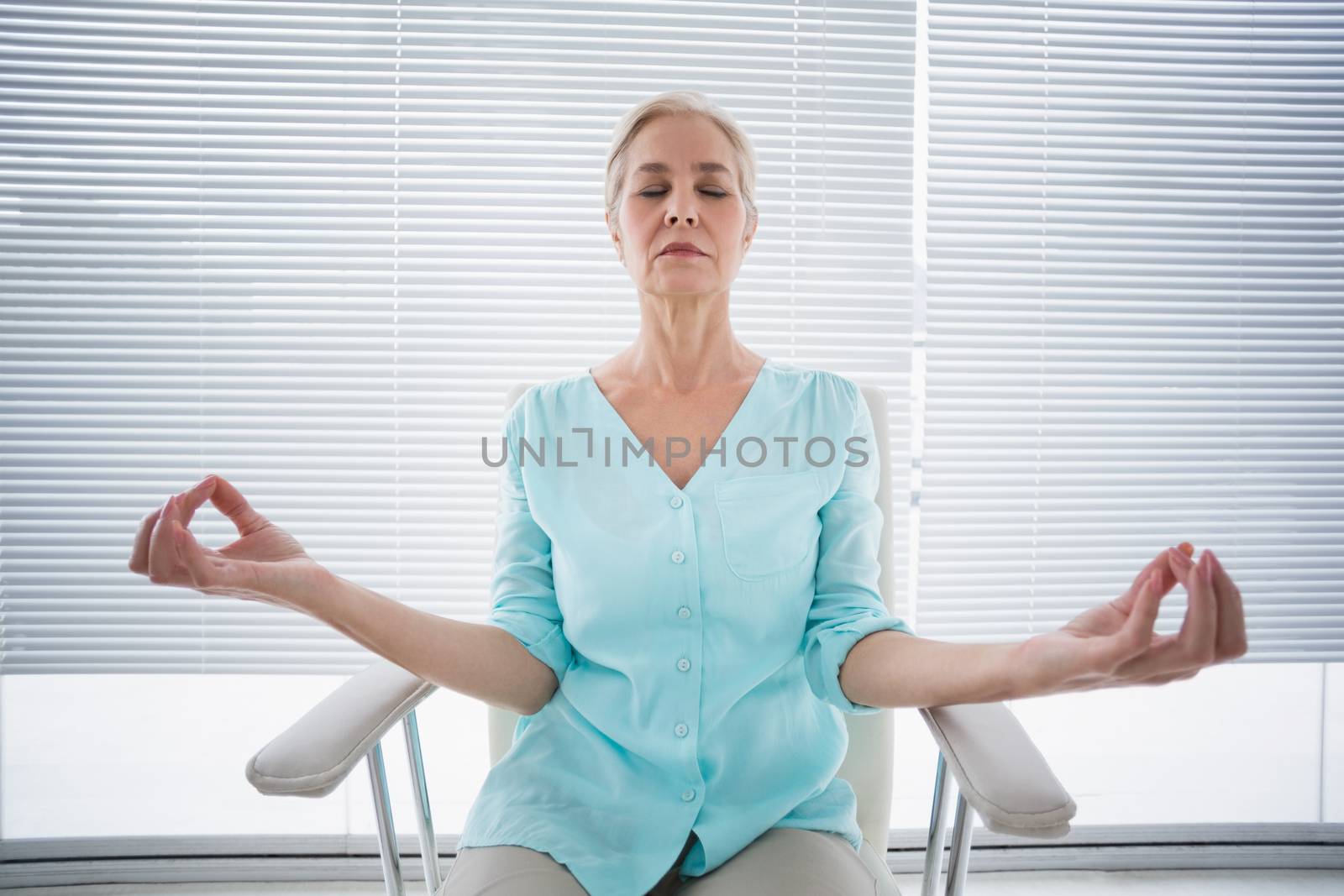 Senior woman doing yoga on chair at fitness studio
