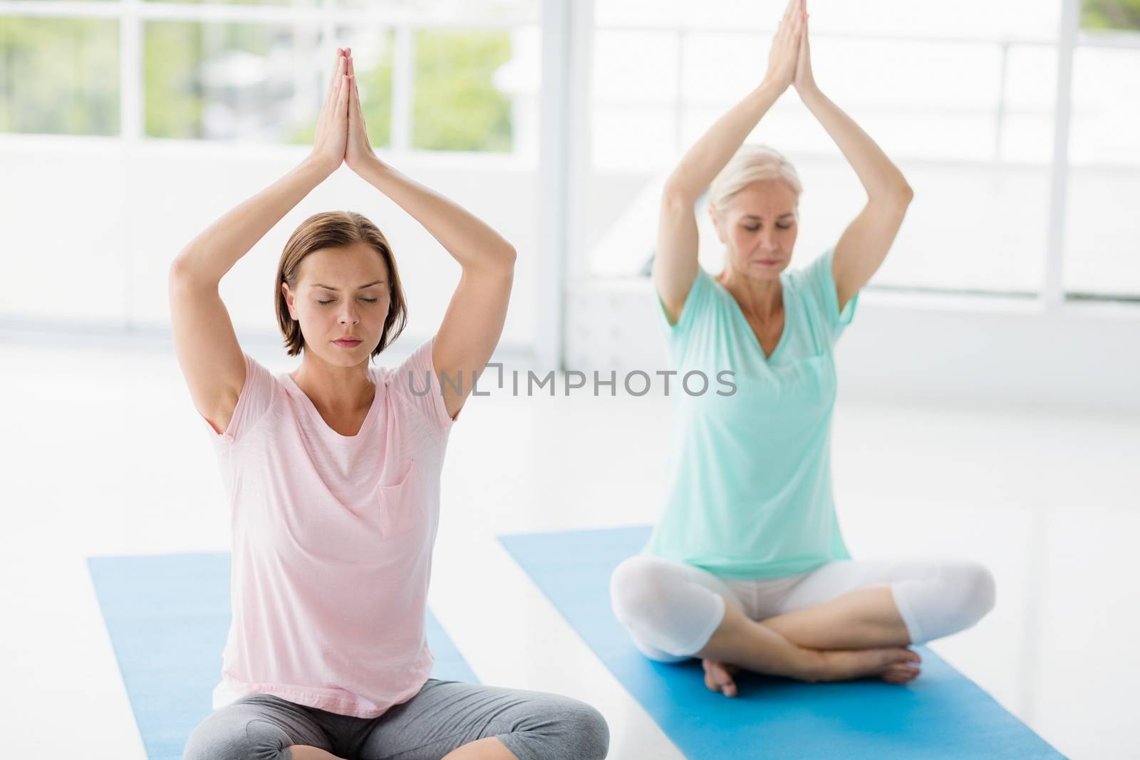 Women with hands clasped doing yoga at fitness studio