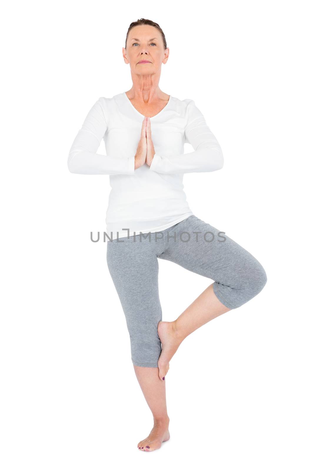 Full length of mature woman in tree pose while exercising on white background